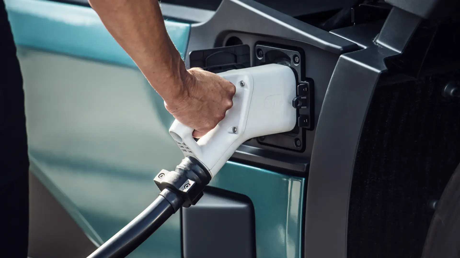 Driver plugging a charging connector into an electric van