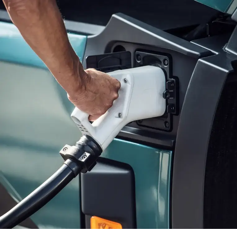 Driver plugging a charging connector into an electric van